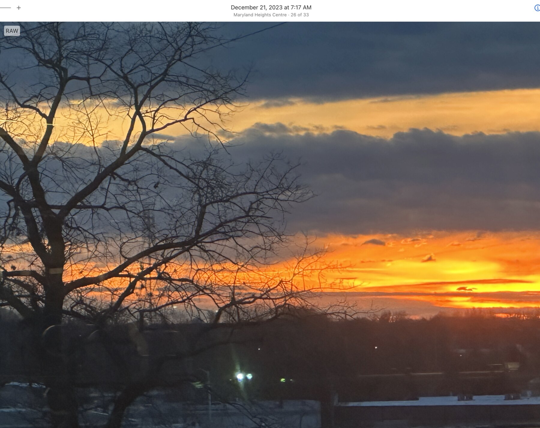 Orange horizon framed by tree branches in Maryland Heights