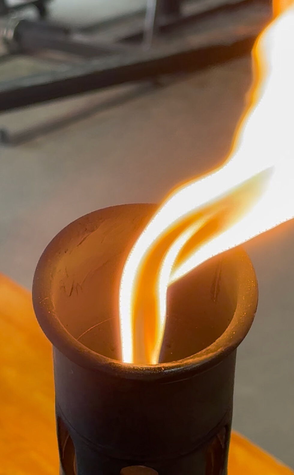 Tall white and orange flame rising from a dark vessel